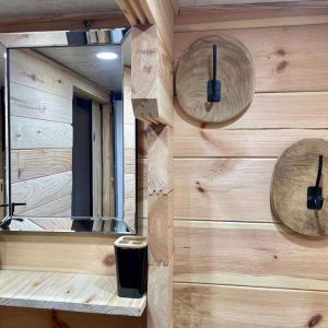 Hébergement insolite en bois à Midi-Pyrénées, avec miroir moderne et décor naturel.