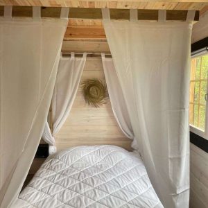 Cabane cosy en Midi-Pyrénées, lit douillet entouré de rideaux blancs.