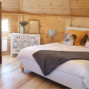 Hébergement insolite en cabane avec lit douillet et décor en bois chaleureux.