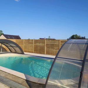 Hébergement insolite avec piscine couverte, entouré dune clôture en bois.