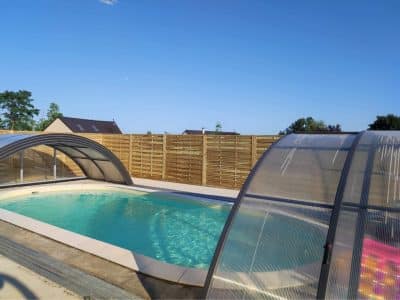 Hébergement insolite avec piscine couverte, entouré dune clôture en bois.