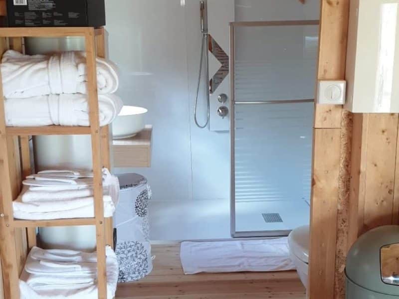 Chalet en bois avec salle de bain moderne et étagère de serviettes.