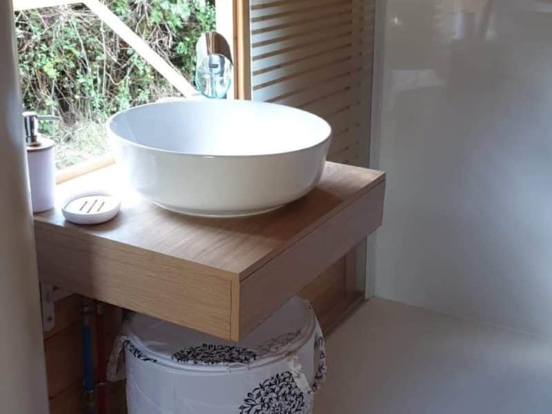 Cabane en bois avec lavabo moderne et vue sur la nature.