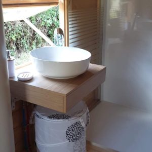 Hébergement insolite en bois avec lavabo moderne et vue sur la nature.