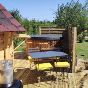 Hébergement insolite en bois avec terrasse, barbecue et jacuzzi à ciel ouvert.