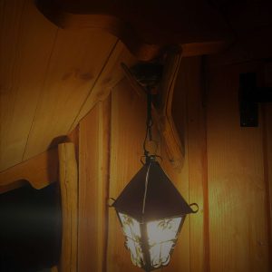 Lanterne vintage suspendue dans un hébergement insolite en bois en Midi-Pyrénées.