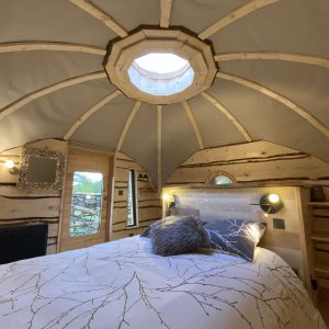 Hébergement insolite en Midi-Pyrénées : cabane en bois avec un lit douillet et un puits de lumière.