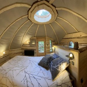 Hébergement insolite en Midi-Pyrénées : cabane en bois avec un toit arrondi et fenêtre ronde.