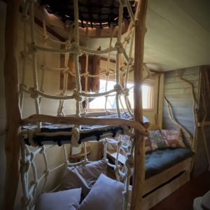 Cabane perchée en Midi-Pyrénées, avec un escalier en corde et un coin salon cosy.