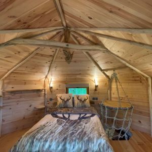 Cabane en bois avec intérieur chaleureux, lit confortable et décor naturel.
