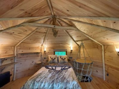 Cabane en bois avec intérieur chaleureux, lit confortable et décor naturel.