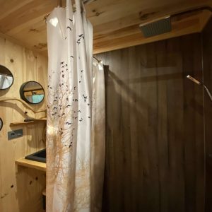 Douche en bois dans un hébergement insolite à Midi-Pyrénées, ambiance chaleureuse.