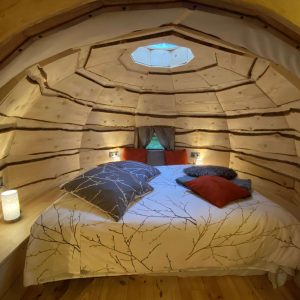 Hébergement insolite en Midi-Pyrénées : cabane en bois avec lit douillet et lumière douce.