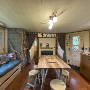 Cabane en bois cosy avec un salon lumineux et une table en bois naturel.