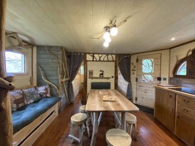 Cabane en bois cosy avec un salon lumineux et une table en bois naturel.