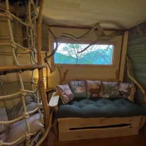 Cabane en bois avec un coin salon cosy et une vue sur la nature environnante.