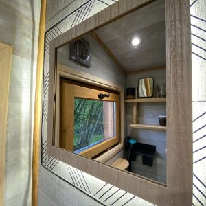 Cabane moderne en bois avec un miroir décoratif et vue sur la nature environnante.