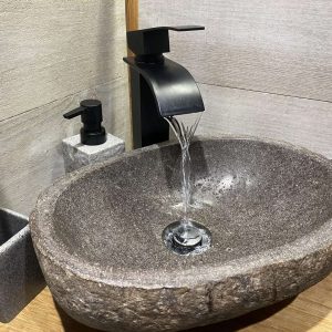 Lavabo en pierre naturelle dans un hébergement insolite en Midi-Pyrénées. Élégance rustique.