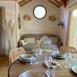 Cabane en bois en Auvergne, intérieur lumineux avec table élégamment dressée.