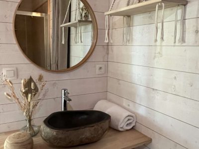 Hébergement insolite en Auvergne : salle de bain moderne avec lavabo en pierre et miroir rond.