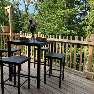 Cabane perchée en Auvergne avec terrasse en bois et vue sur la nature verdoyante.