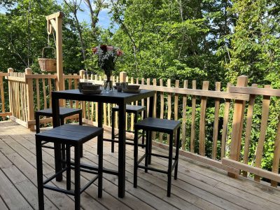 Cabane perchée en Auvergne avec terrasse en bois et vue sur la nature verdoyante.