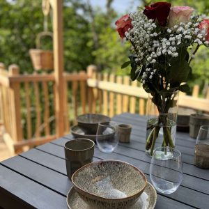 Hébergement insolite en Auvergne avec une terrasse, décorée de fleurs et vaisselle élégante.