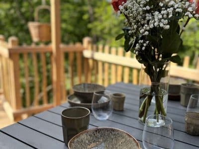 Hébergement insolite en Auvergne avec une terrasse, décorée de fleurs et vaisselle élégante.