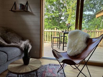 Hébergement insolite en Auvergne : chalet moderne avec vue sur la nature et fauteuil en cuir.
