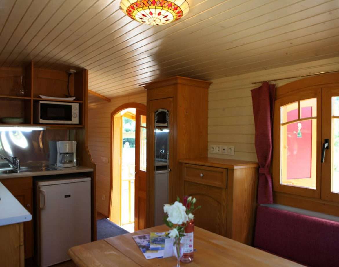 Intérieur chaleureux dun chalet en bois, avec cuisine équipée et lumière tamisée.