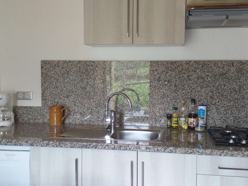 Cuisine moderne dun appartement, avec un plan de travail en granit et des équipements complets.