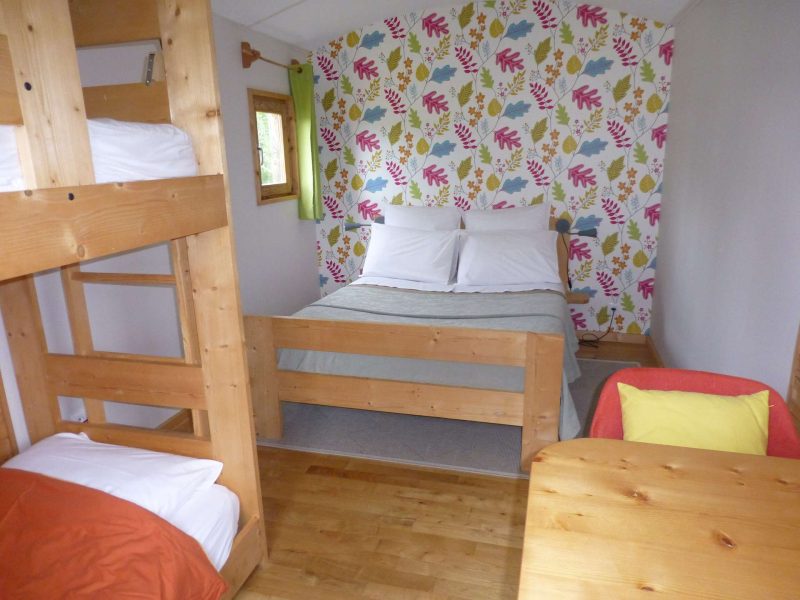 Chalet cosy avec lits superposés, décor floral et ambiance chaleureuse.