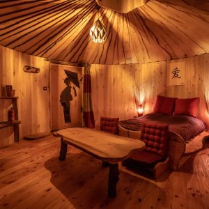 Hébergement insolite : yourte en bois avec lit douillet et ambiance chaleureuse.