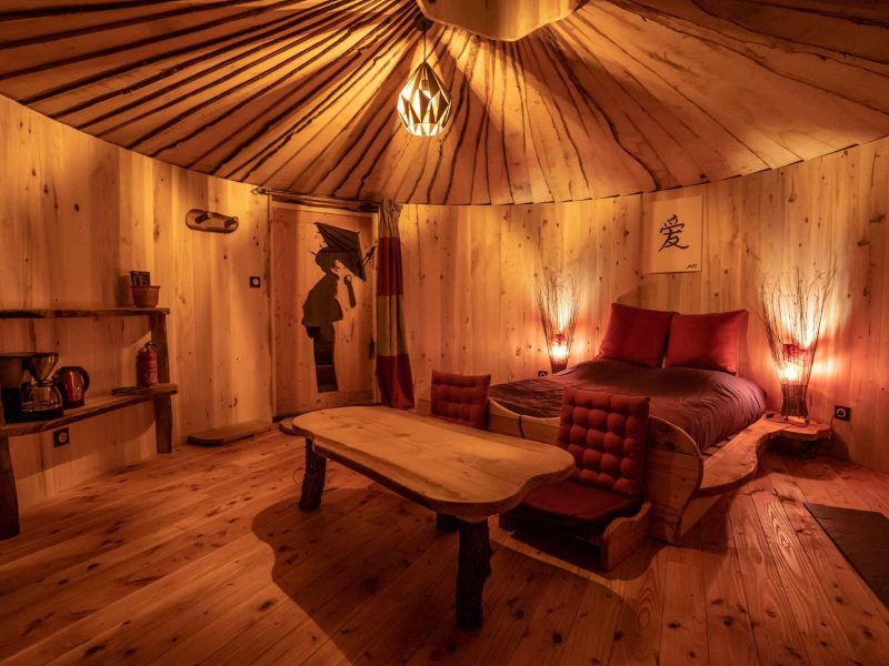 Hébergement insolite : yourte en bois avec lit douillet et ambiance chaleureuse.