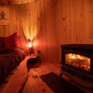 Hébergement insolite en bois avec lit douillet et poêle à bois chaleureux.