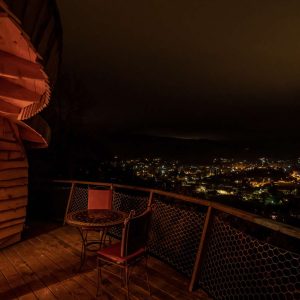 Cabane perchée à Languedoc-Roussillon, vue nocturne sur la ville illuminée.