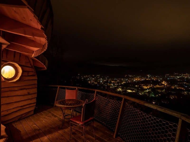 Cabane perchée à Languedoc-Roussillon, vue nocturne sur la ville illuminée.