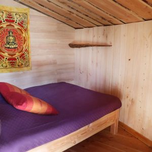 Chalet en bois avec lit douillet et décoration colorée au Languedoc-Roussillon.