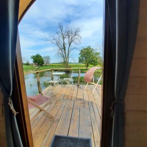 Cabane sur pilotis avec vue sur un étang et chaises confortables.
