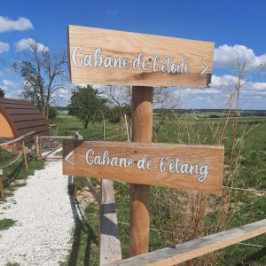 Cabane de létoile et cabane de létang, entourées de verdure et ciel bleu.