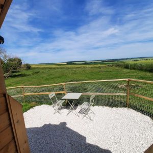 Cabane en bois avec vue dégagée sur la campagne et terrasse en gravier.