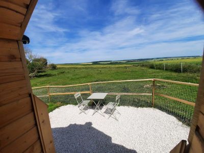 Cabane en bois avec vue dégagée sur la campagne et terrasse en gravier.