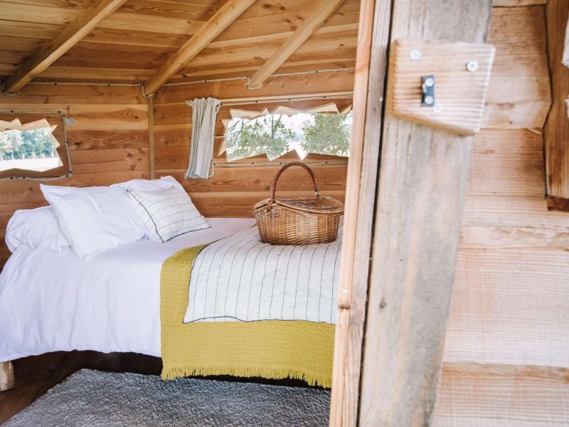 Cabane en bois avec lit douillet et panier en osier sur le couvre-lit.