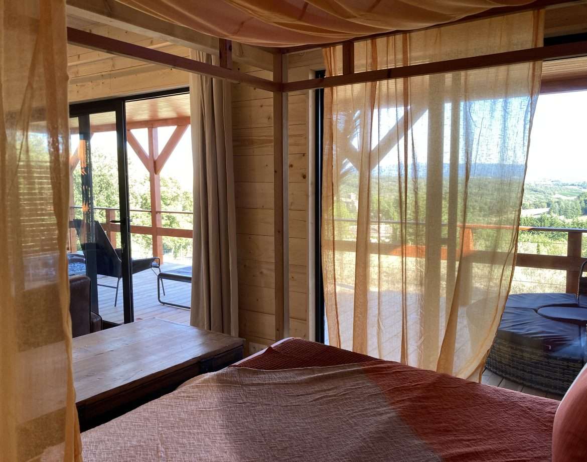 Chalet en bois avec vue panoramique, drapés légers et ambiance chaleureuse.