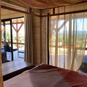 Chalet en bois avec vue panoramique, drapés légers et ambiance chaleureuse.