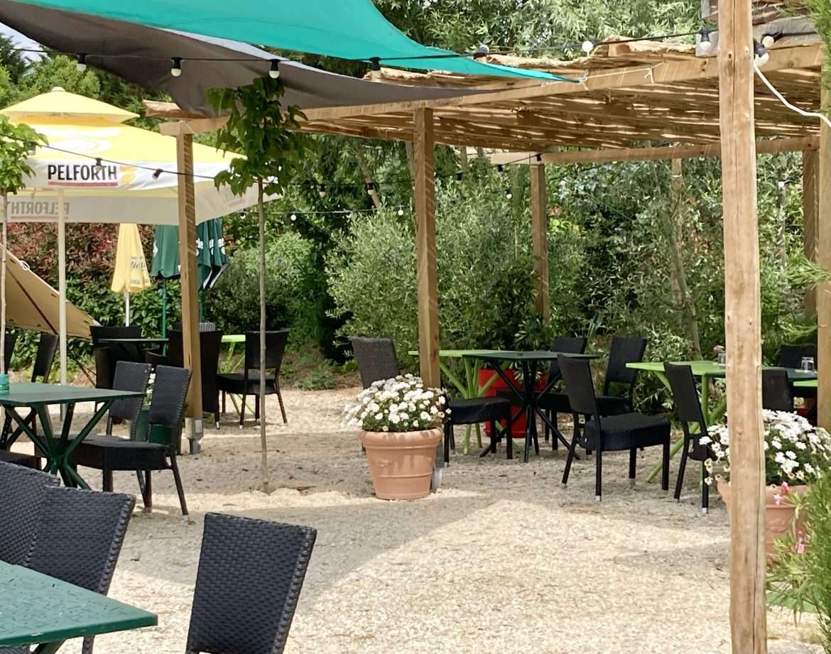 Espace extérieur dun hébergement insolite avec tables et parasols colorés.