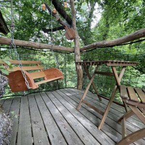Cabane perchée en Aquitaine avec balancelle en bois et vue sur la nature environnante.