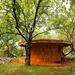 Cabane en bois ronde, nichée dans la verdure du Languedoc-Roussillon.