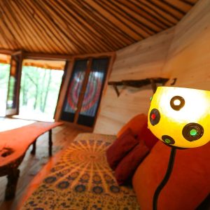 Hébergement insolite en yourte, intérieur chaleureux avec lampes colorées et bois naturel.