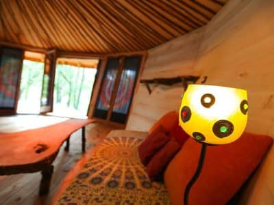 Hébergement insolite en yourte, intérieur chaleureux avec lampes colorées et bois naturel.